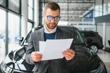 Adam akıllı müşteri, takım elbiseli müşteri, otomobili seçer, kenara bakar, galeride yeni otomobil almak ister.