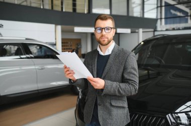 Adam akıllı müşteri, takım elbiseli müşteri, otomobili seçer, kenara bakar, galeride yeni otomobil almak ister.
