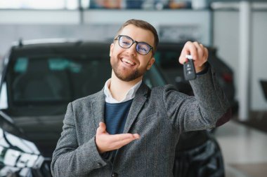 Yeni bir arabanın mutlu sahibi. Günlük giysiler içinde duygusal açıdan yakışıklı bir adam, galeriden bir araba almaktan mutlu.