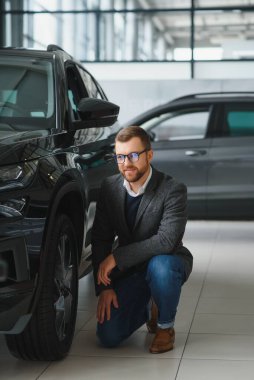 Adam akıllı müşteri, takım elbiseli müşteri, otomobili seçer, kenara bakar, galeride yeni otomobil almak ister.