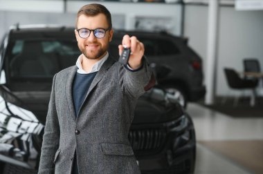 Adam akıllı müşteri, takım elbiseli müşteri, otomobili seçer, kenara bakar, galeride yeni otomobil almak ister.