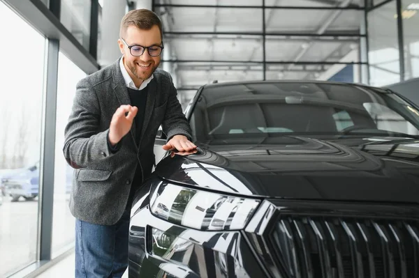 stock image Visiting car dealership. Handsome bearded man is stroking his new car and smiling.