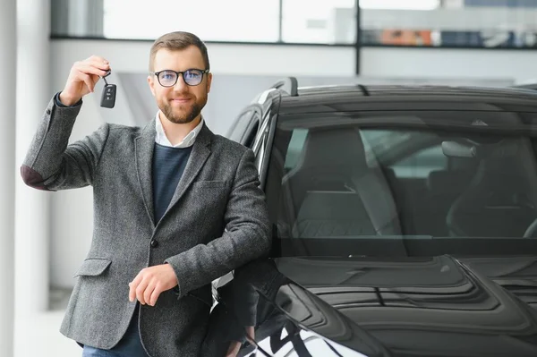 stock image Yes, that's my new car. Customer in car dealership. Young man knelt down with keys in hand