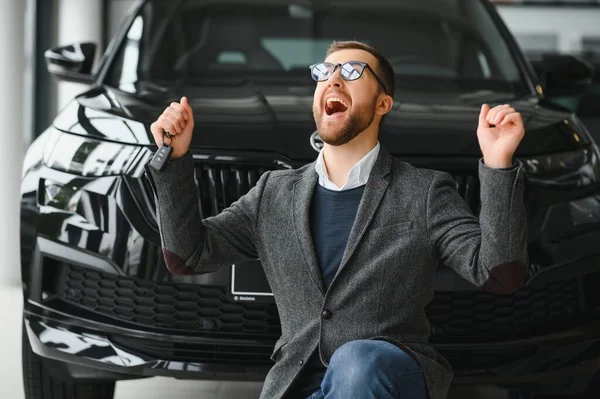 stock image Yes, that's my new car. Customer in car dealership. Young man knelt down with keys in hand