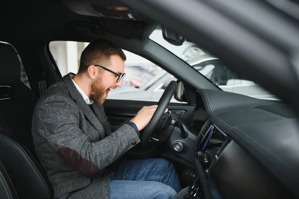 stock image Visiting car dealership. Handsome bearded man is stroking his new car and smiling.