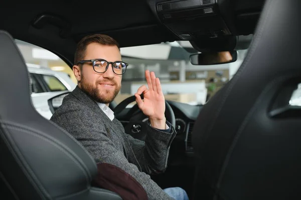 stock image Visiting car dealership. Handsome bearded man is stroking his new car and smiling.