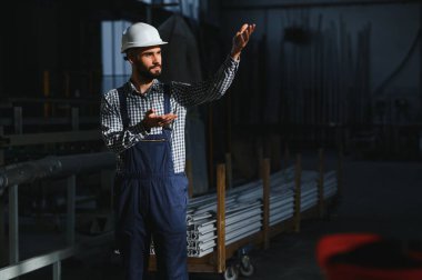 Endüstriyel mühendis portresi. Fabrikada çalışan kasklı bir fabrika işçisi.
