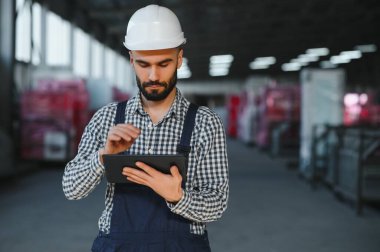 Fabrika teknisyeni fabrika deposunda dijital tablet kullanıyor.