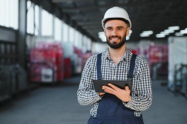 Fabrika teknisyeni fabrika deposunda dijital tablet kullanıyor.