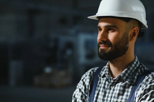 Happy Professional Heavy Industry Engineer Worker Wearing Uniform, and Hard Hat in a Steel Factory. Smiling Industrial Specialist Standing in a Metal Construction Manufacture.