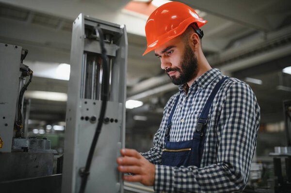 Portrait of industrial engineer. Factory worker with hard hat standing in factory