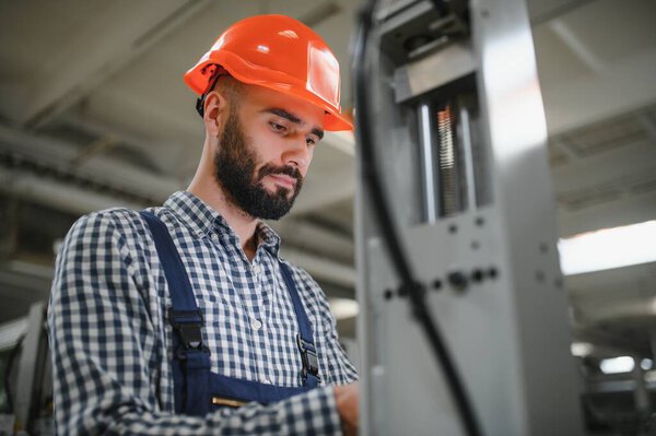 Работник мужской фабрики, работающий или работающий с машиной на промышленном заводе в форме безопасности и в каске