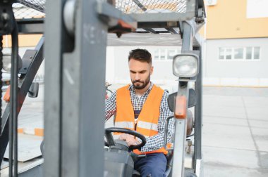 Depoda çalışan ve forklift kullanan bir adam..