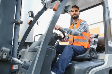 Forklift kullanırken bir nakliye şirketinin deposunda forklift sürüyordu..