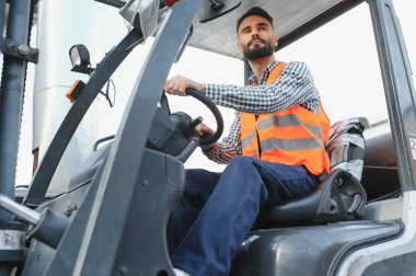 Forklift kullanırken bir nakliye şirketinin deposunda forklift sürüyordu..