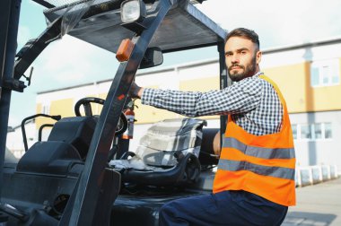 Depoda çalışan ve forklift kullanan bir adam..