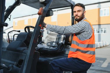 Forklift kullanırken bir nakliye şirketinin deposunda forklift sürüyordu..
