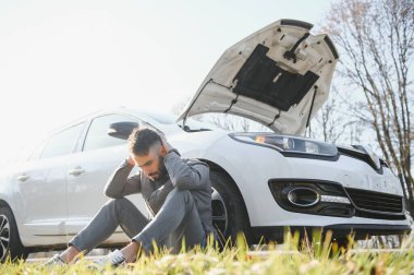 Hüsrana uğramış üzgün adam, araba kazasından sonra kaza yapmış bir arabanın yanında oturuyor. Genç, şok olmuş, korkmuş, korkmuş bir adam trafik kazası geçirmiş, asfaltta oturmuş, elleriyle başını tutuyormuş..