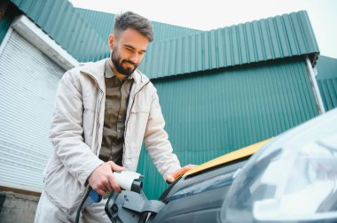 Dışarıdaki otoparkta elektrikli araba için elektrik kablosu. Ve arabayı alışveriş merkezinin yanındaki park yerindeki şarj istasyonuna bağlayacak..