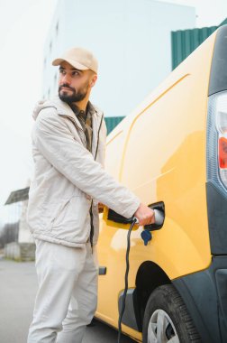 Dışarıdaki otoparkta elektrikli araba için elektrik kablosu. Ve arabayı alışveriş merkezinin yanındaki park yerindeki şarj istasyonuna bağlayacak..