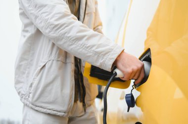 Şarj kablosunun yanında duran genç bir adamın portresi..