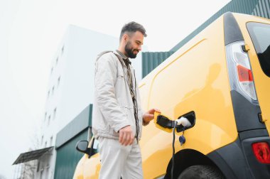 Şarj kablosunun yanında duran genç bir adamın portresi..