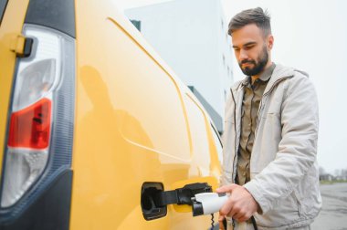 Dışarıdaki otoparkta elektrikli araba için elektrik kablosu. Ve arabayı alışveriş merkezinin yanındaki park yerindeki şarj istasyonuna bağlayacak..