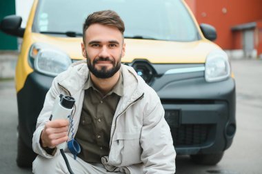 Dışarıdaki otoparkta elektrikli araba için elektrik kablosu. Ve arabayı alışveriş merkezinin yanındaki park yerindeki şarj istasyonuna bağlayacak..