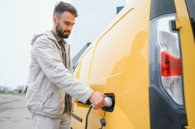 Şarj kablosunun yanında duran genç bir adamın portresi..