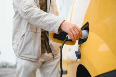 Elektrikli otomobil için güç konektörü tutan adam.