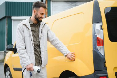 Dışarıdaki otoparkta elektrikli araba için elektrik kablosu. Ve arabayı alışveriş merkezinin yanındaki park yerindeki şarj istasyonuna bağlayacak..