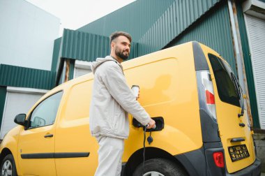 Elektrikli otomobil için güç konektörü tutan adam.