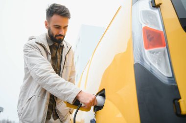 Dışarıdaki otoparkta elektrikli araba için elektrik kablosu. Ve arabayı alışveriş merkezinin yanındaki park yerindeki şarj istasyonuna bağlayacak..