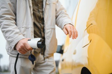 Şarj kablosunun yanında duran genç bir adamın portresi..