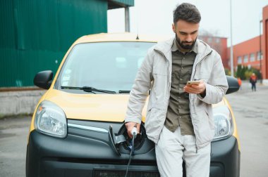 Şarj kablosunun yanında duran genç bir adamın portresi..