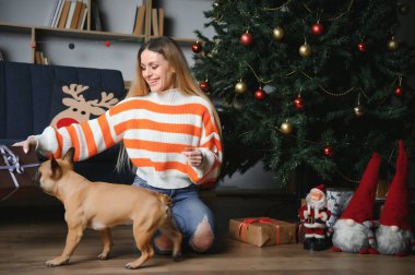 Noel 'in arka planında bir köpekle kanepede oturan güzel kız..