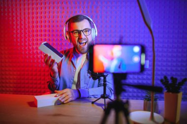 Kanal için online içerik oluşturan genç bir adam, günlük vlog, evde yepyeni bir telefon açmak, çevrimiçi satışlar.