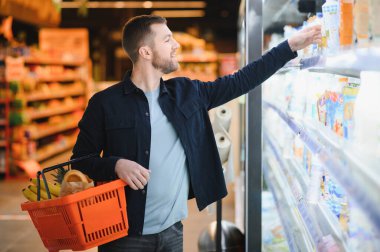 Yakışıklı adam, modern süpermarketten ya da marketten sağlıklı yiyecek ve içecek alıyor. Yaşam tarzı ve tüketim konsepti