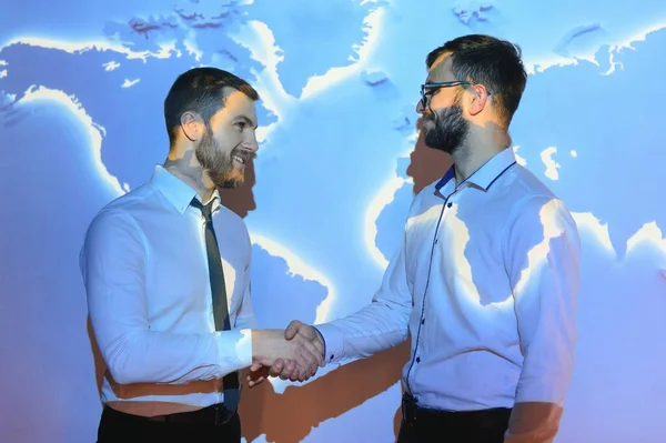 Handshake with map of the world in background.