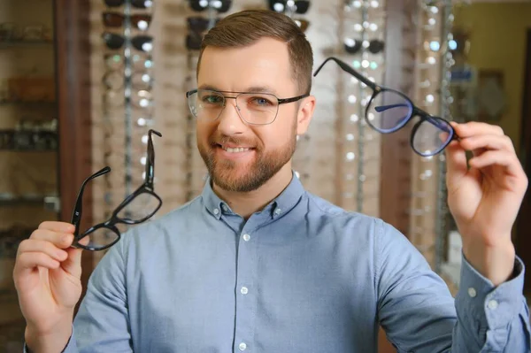 stock image Big choice. Stylish man with beard choosing glasses in the optics store