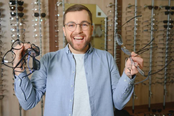 Man is choosing glasses in optics store