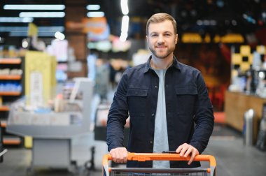 Süpermarketteki müşteri. Market alışverişi yapan bir adam, araba ile ayakta duruyor, içeride yiyecek seçiyor. Afro-Amerikalı Adam Gıda Mağazasından alışveriş yapıyor. Seçici Odaklanma, Boşluğu Kopyala