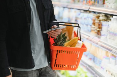 Yakışıklı genç adam süpermarkette yemek seçiyor..