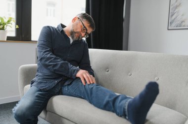 kişi, sağlık ve sorun kavramı - mutsuz üst düzey adam diz acı evde ağrıyor.