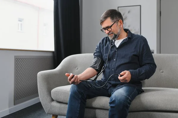 stock image Senior man using medical device to measure blood pressure.