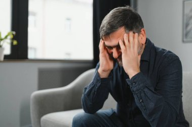 Baş ağrısı. Yaşlı adam evde oturan migren ağrısı çeken masaj tapınaklarından muzdarip. Yaşlılıkta Sağlık ve Sağlık Sorunları Konsepti.