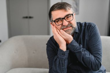 Diş Bakımı, Diş Hassasiyeti Konsepti. Korkunç diş ağrısından muzdarip mutsuz olgun bir adamın portresi, dokunaklı yanak ağrısı, evde kanepede oturan yaşlı bir erkek, bedava fotokopi alanı..