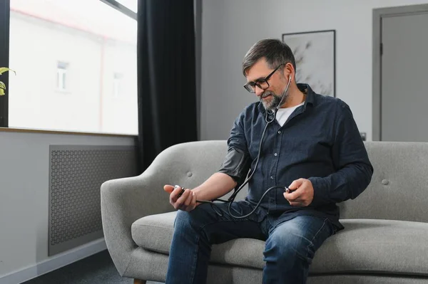 stock image Senior caucasian retired male taking blood pressure at home.