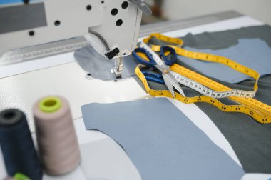 Beyaz bir masa üzerinde dikiş ipliği, makas ve mezura bileşimi. Bir giyim tasarımcısı kavramı.