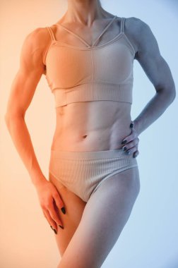 Beyaz stüdyo arka planında fotokopi alanı olan iç çamaşırlı genç ve sportif bir kadın. Spor, diyet, vücut bakımı, kadın güzellik konsepti.